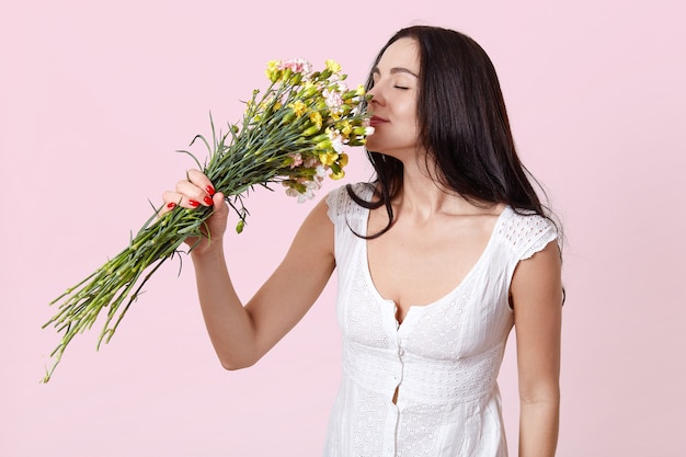 Ritratto di dolce giovane donna dai capelli scuri, vestito in abito bianco