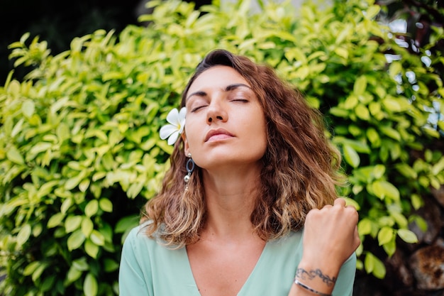 Ritratto di donna abbronzata europea sorridente felice con capelli ricci corti in abito estivo romantico manica lunga fuori dalla villa