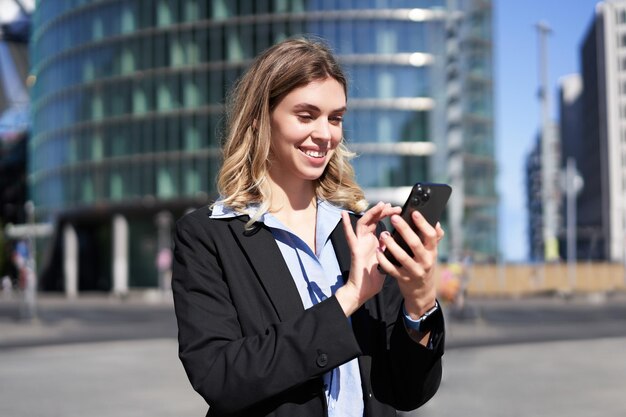 Ritratto di donna aziendale sicura che utilizza il telefono cellulare sulla messaggistica di una donna d'affari di strada di città su s