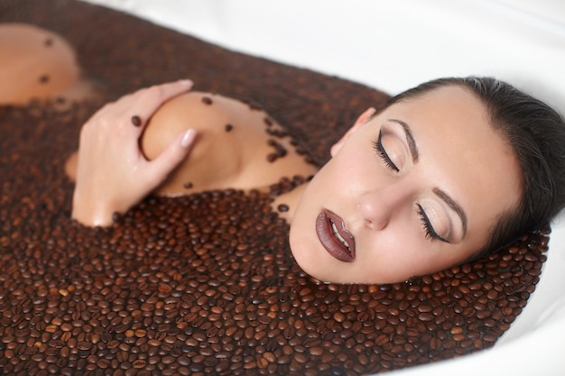 Ritratto di donna bella moda nella vasca idromassaggio con caffè. Cura del corpo. trucco luminoso