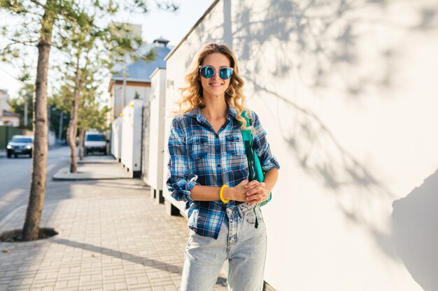 Ritratto di donna bionda felice sorridente alla moda che cammina in strada in camicia blu