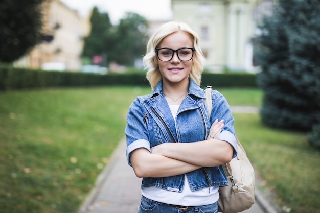 Ritratto di donna bionda in città che indossa jeans suite al mattino