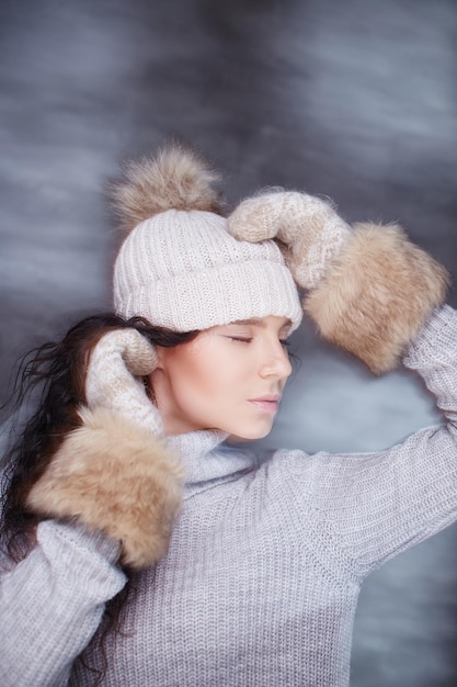 Ritratto di donna bruna con cappello invernale e guanti di pelliccia.