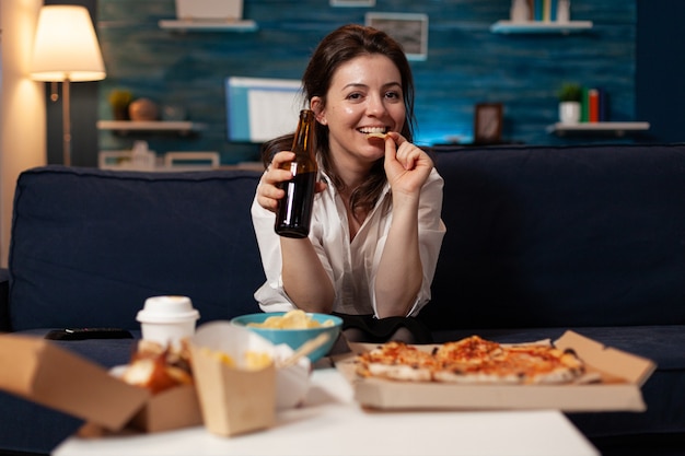 Ritratto di donna caucasica che guarda nella telecamera tenendo in mano una bottiglia di birra