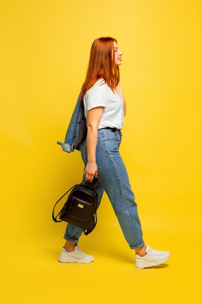 Ritratto di donna caucasica su sfondo giallo. Bello modello femminile dei capelli rossi.