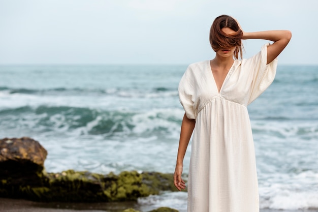 Ritratto di donna che copre il viso con i capelli in spiaggia