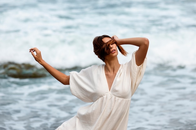 Ritratto di donna che copre il viso con i capelli in spiaggia