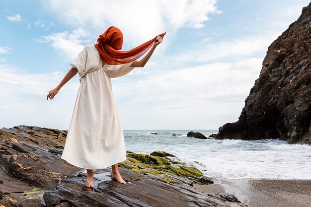 Ritratto di donna che copre il viso con il velo in spiaggia