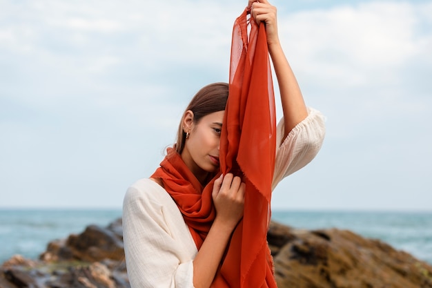 Ritratto di donna che copre il viso con il velo in spiaggia