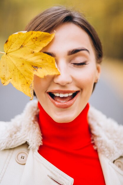 Ritratto di donna che copre mezza faccia con una foglia