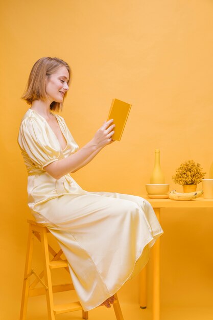 Ritratto di donna che legge un libro in una scena gialla