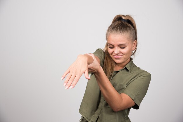 Ritratto di donna che offre la sua mano sul muro grigio.