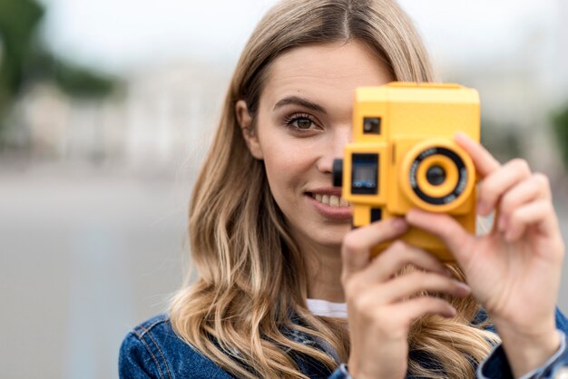 Ritratto di donna che tiene una retro macchina fotografica gialla