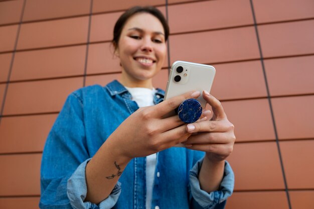 Ritratto di donna che utilizza smartphone con presa pop all'aperto