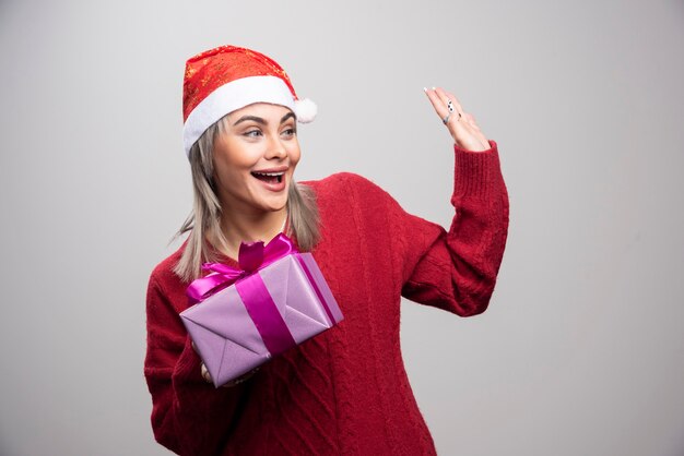 Ritratto di donna con scatola regalo che saluta qualcuno.