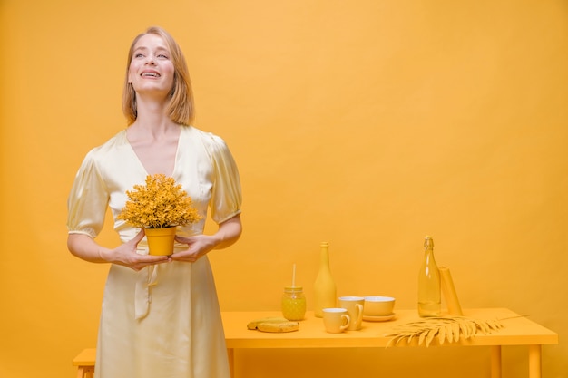 Ritratto di donna con un vaso di fiori in una scena gialla