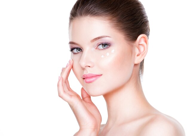 Ritratto di donna con viso sano, applicare la crema cosmetica sotto gli occhi.