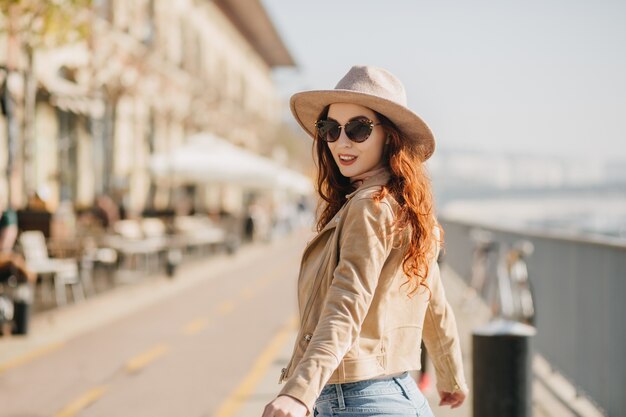 Ritratto di donna di zenzero che ride guardando sopra la spalla mentre si cammina per strada