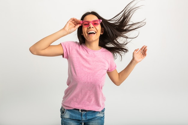 Ritratto di donna emotiva abbastanza sorridente in camicia rosa e occhiali da sole alla moda, denti bianchi, posa positiva isolata, capelli lunghi