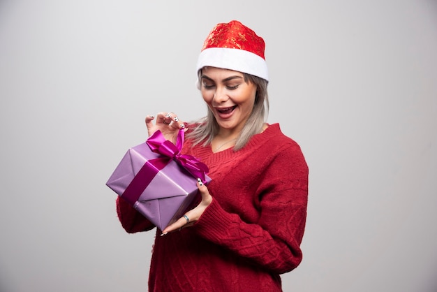 Ritratto di donna felice che prova ad aprire il suo regalo di festa.