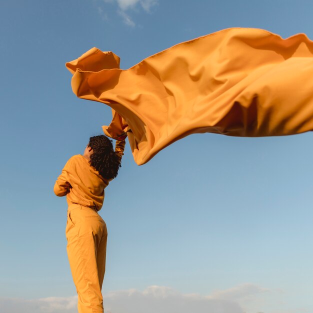 Ritratto di donna gioiosa con un panno giallo in natura