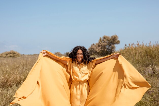 Ritratto di donna gioiosa con un panno giallo in natura