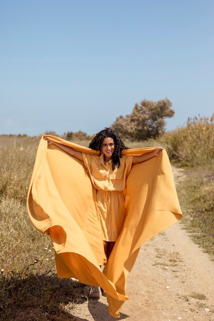 Ritratto di donna gioiosa con un panno giallo in natura