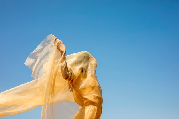 Ritratto di donna gioiosa con un panno giallo in natura