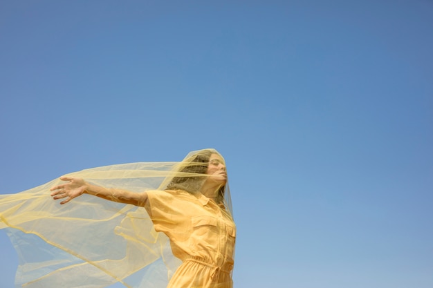 Ritratto di donna gioiosa con un panno giallo in natura