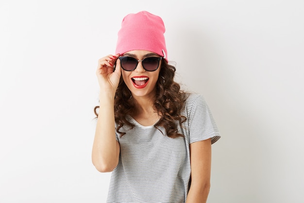 Ritratto di donna graziosa hipster con espressione faccia buffa uscita, emotivo, in cappello rosa, occhiali da sole, sorridente, umore felice, denti bianchi, isolato, labbra rosse, capelli ricci