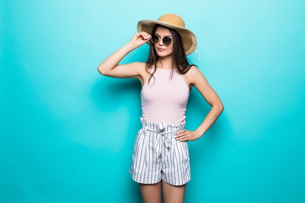Ritratto di donna graziosa in occhiali da sole e cappello su blu colorato. Concetto di estate.