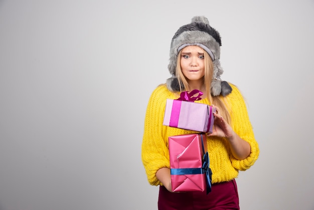 Ritratto di donna in cappello che trasporta i regali di Natale.