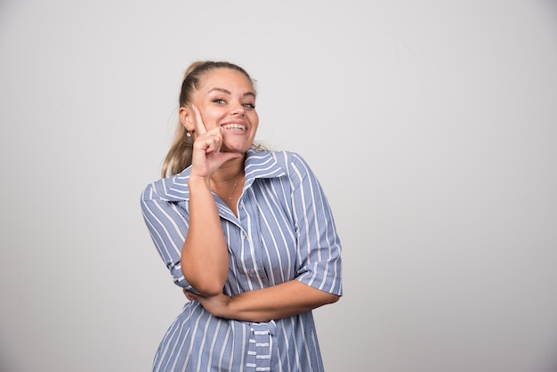 Ritratto di donna in posa felicemente sul muro grigio.