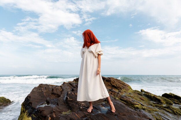 Ritratto di donna in spiaggia che copre il viso con il velo