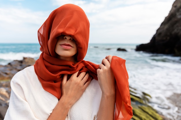 Ritratto di donna in spiaggia che copre il viso con il velo