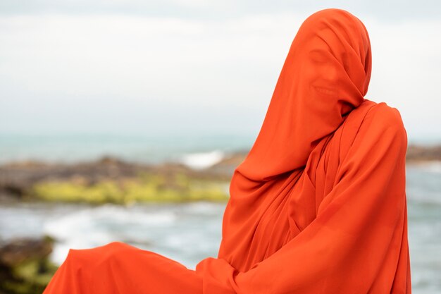 Ritratto di donna in spiaggia con il viso coperto da velo