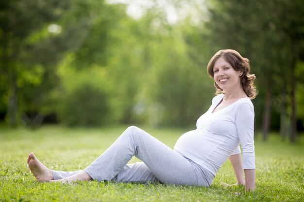 Ritratto di donna incinta allegra che si distende nel parco