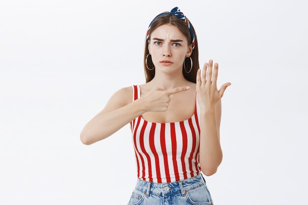 Ritratto di donna interessata che mostra il palmo senza anello nuziale che punta al dito e accigliato essere scontento e infastidito