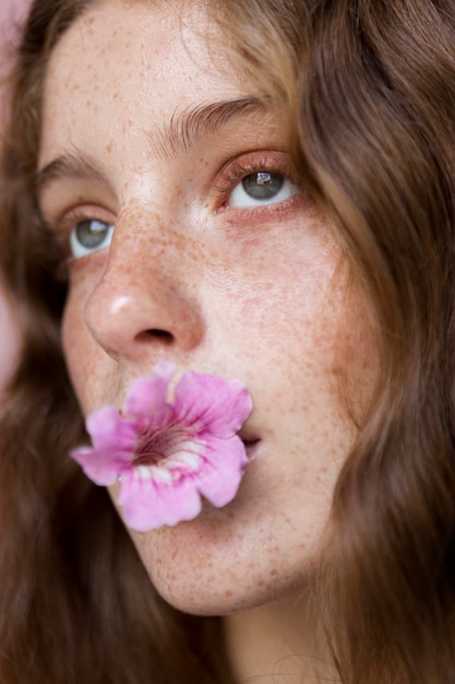 Ritratto di donna lentigginosa con fiore in primo piano bocca