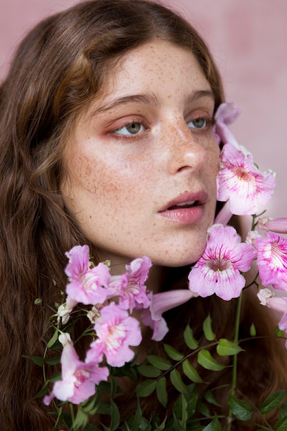 Ritratto di donna lentigginosa tenendo un fiore rosa contro il viso