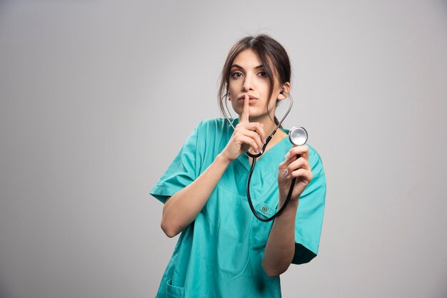 Ritratto di donna medico con stetoscopio su grigio