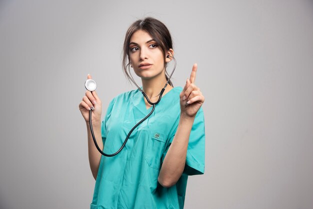 Ritratto di donna medico in posa con lo stetoscopio su grigio