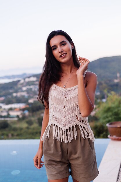 Ritratto di donna romantica calma caucasica felice in look casual con capelli lunghi che indossa orecchini e collana su sfondo incredibile bella vista sulle montagne verdi