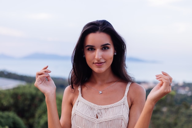 Ritratto di donna romantica calma caucasica felice in look casual con capelli lunghi che indossa orecchini e collana su sfondo incredibile bella vista sulle montagne verdi