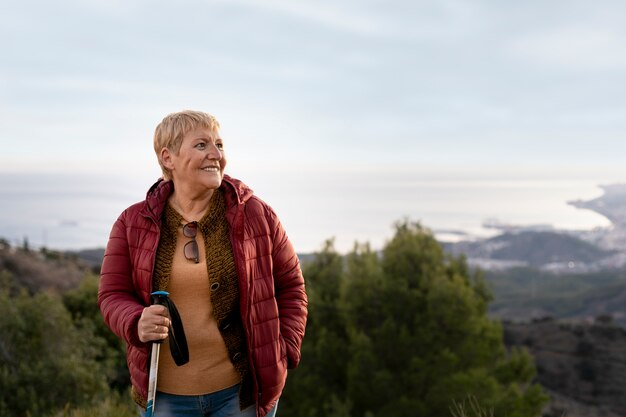 Ritratto di donna senior su un'avventura nella natura che tiene il bastone da trekking