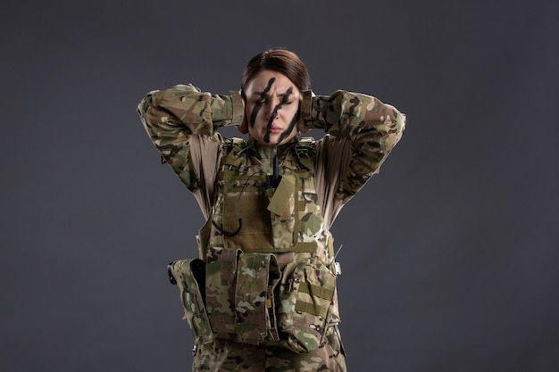 Ritratto di donna soldato in mimetica sul muro scuro