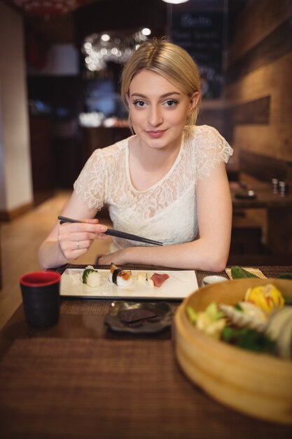 Ritratto di donna sorridente che mangia sushi