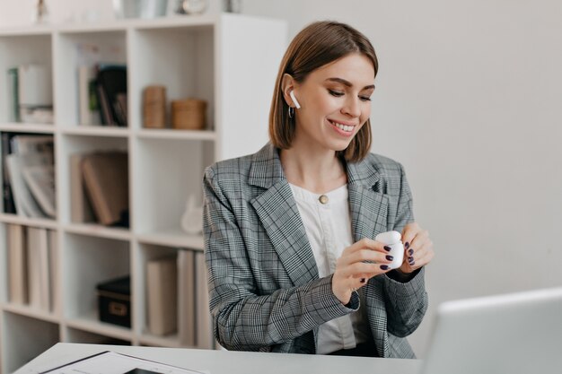 Ritratto di donna sorridente in abito da ufficio che indossa gli airpod per comunicare con i clienti.