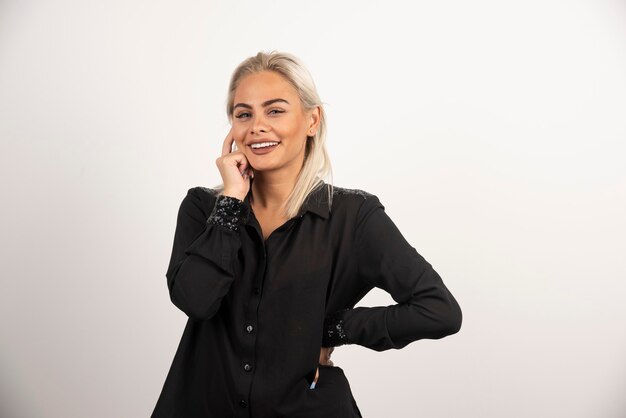 Ritratto di donna sorridente in camicia nera in posa su sfondo bianco. Foto di alta qualità