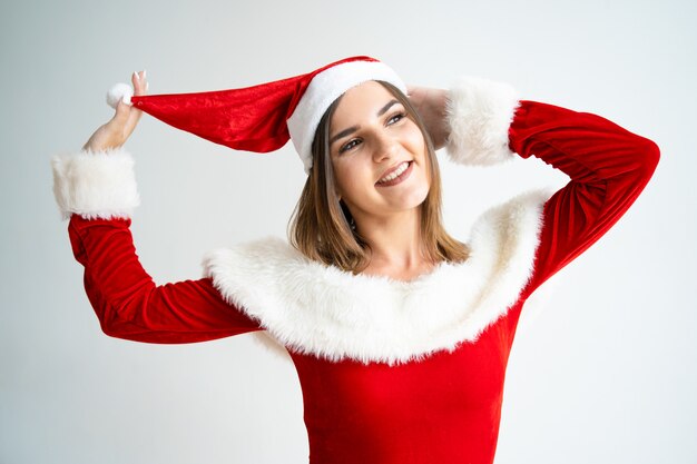 Ritratto di donna spensierata in abito di Babbo Natale giocando con cappello